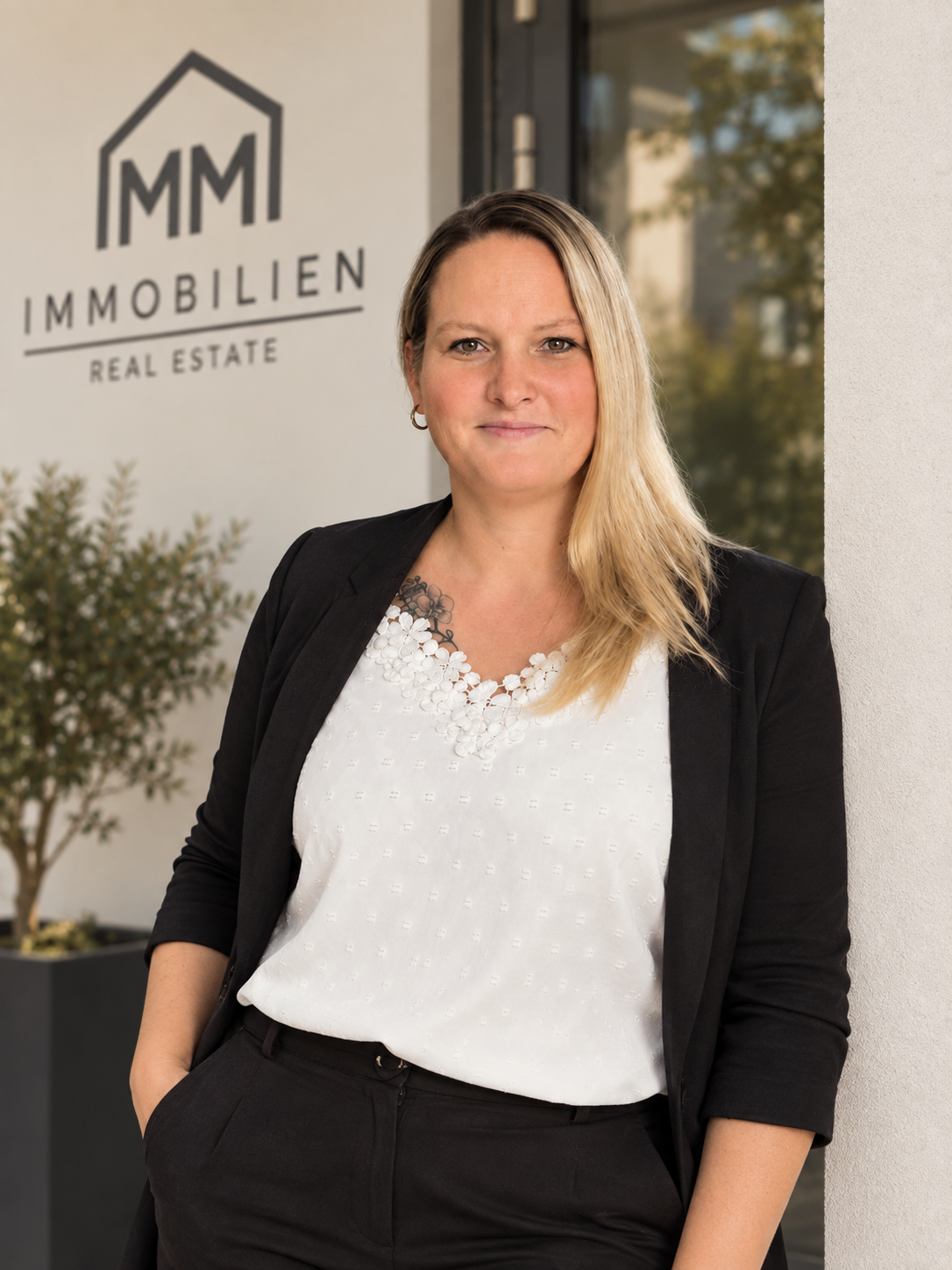 Tamara Horstmann von MM Immobilien vor dem MM Immobilien Logo am Büroeingang